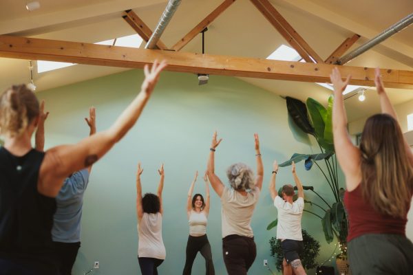People in standing yoga pose with hands raised