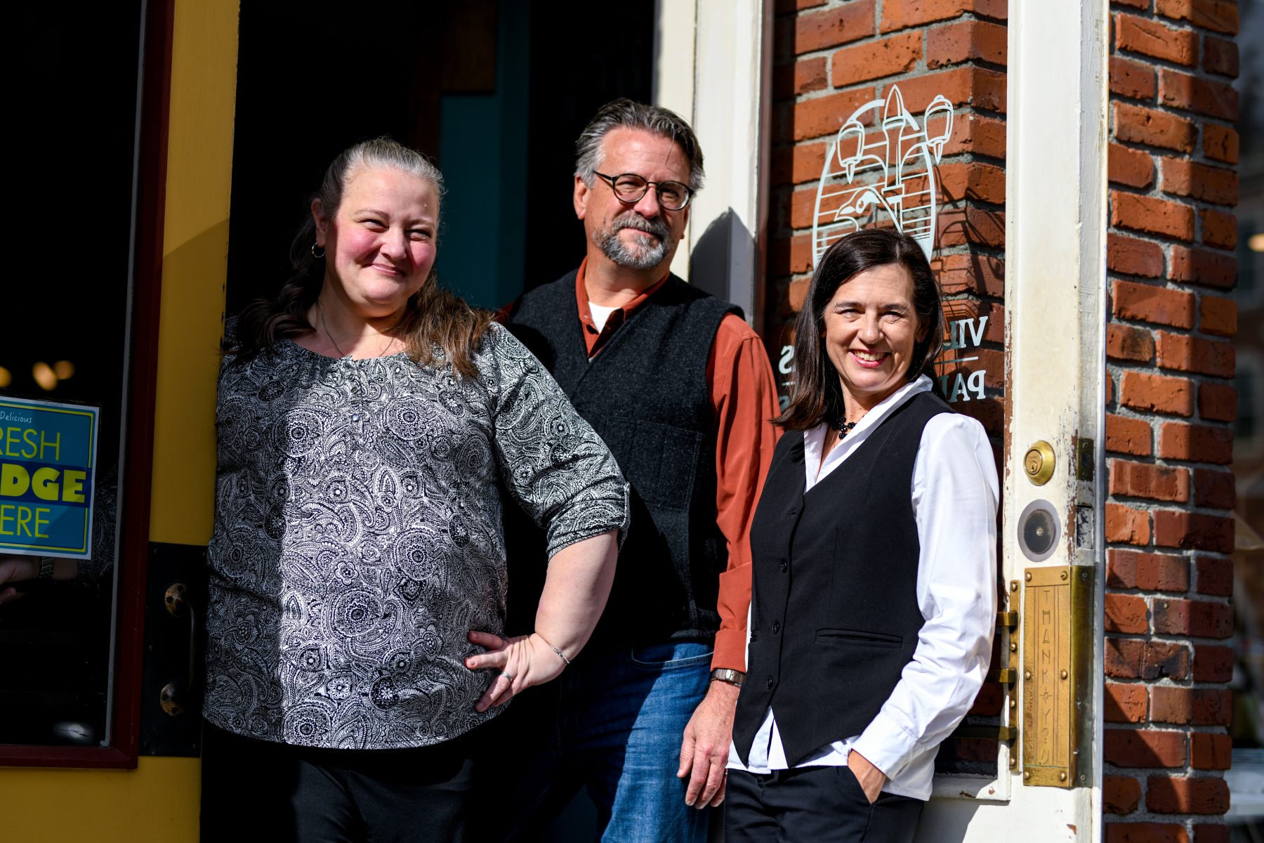The three owners of Village Books smile in the doorway of the Fairhaven shop.