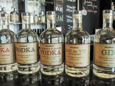 Glass bottles of Bellewood Distilling vodka and gin lined up on a bar.