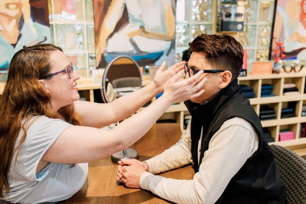 Person at Binyon Vision Center holding glasses up to another person's face
