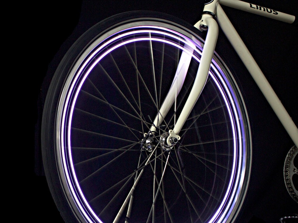 A glowing bicycle wheel light on a bicycle in the dark.
