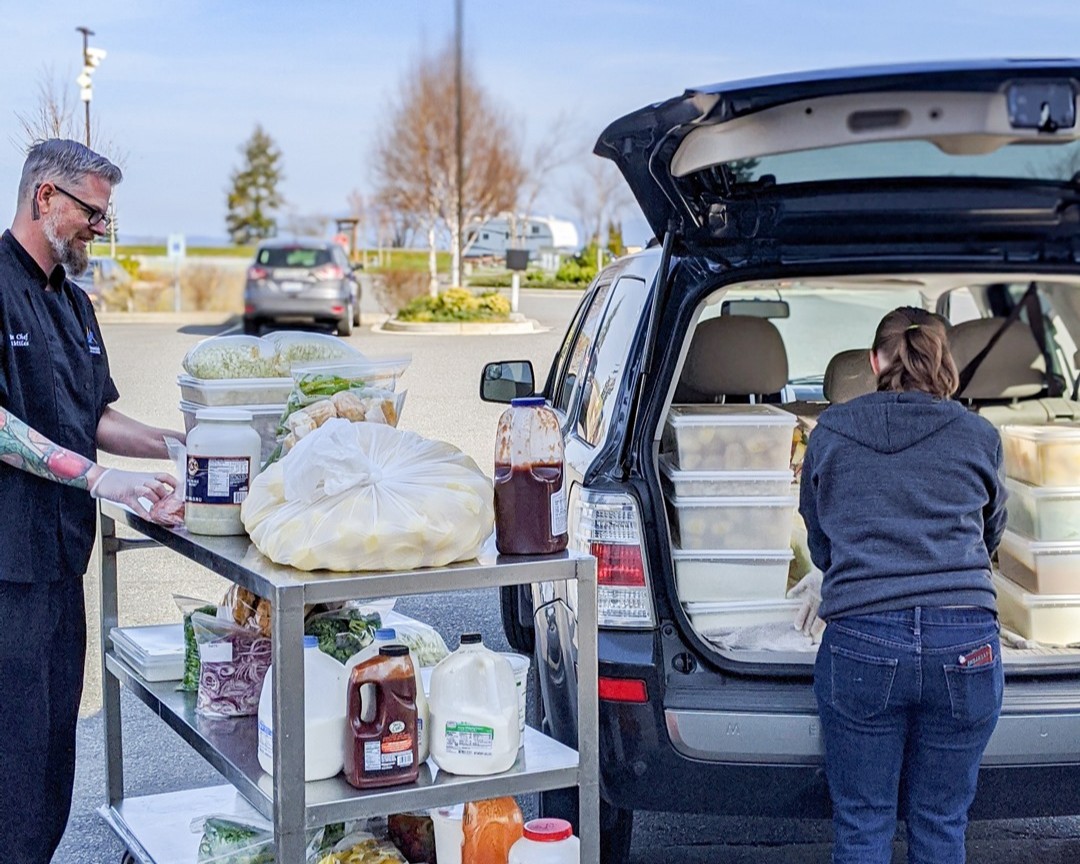 two people with food recovery tubs standing in front of the food recovery van